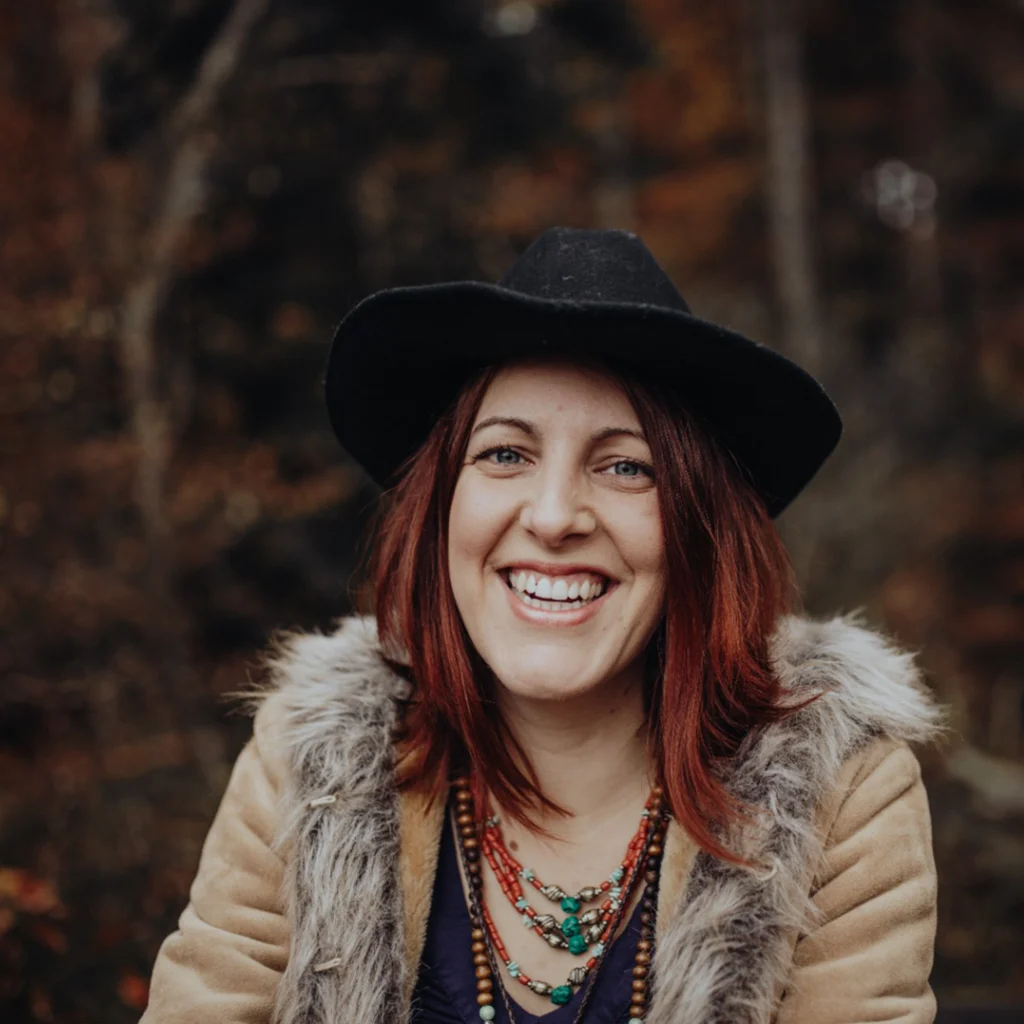 Portrait de Virginie, créatrice de Rosea : chapeau noir, colliers bohèmes et cheveux cuivrés, en forêt